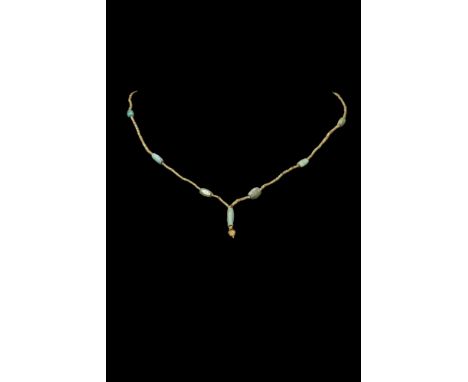 Ca. 100-300 AD.A beaded necklace composed of gold and turquoise beads. A large, tubular turquoise pendant sits at the centre,