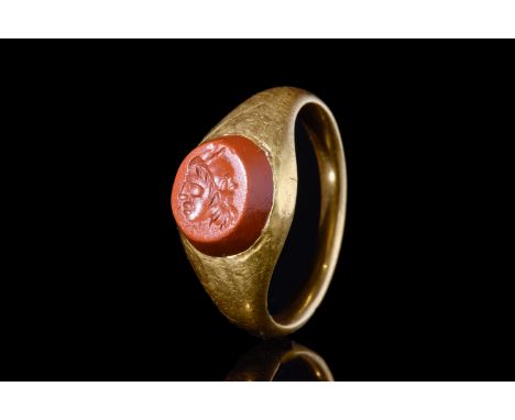 Ca. 100-200 AD.A gold ring with a rounded hoop and subtly flattened interior, holding a convex jasper intaglio. The stone is 