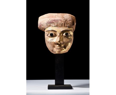 New Kingdom, Ca. 1550-1069 BC.A gilded sarcophagus mask carved from finely-grained cedar wood. It is presented with inlaid ma
