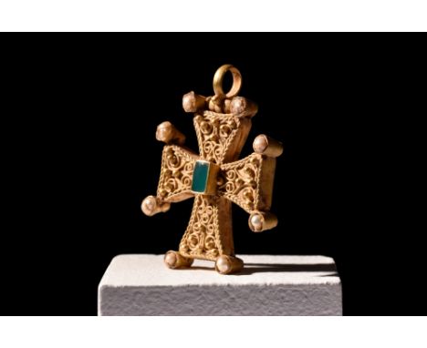 Ca. 600-800 AD. A gold cross pendant, with four arms and a rectangular raised cell in the centre containing a green chalcedon