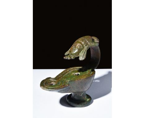 Ca. 100 AD.A Roman oil lamp with a pear-shaped body, a raised foot, and a strap handle with a relief of a theatrical mask. It