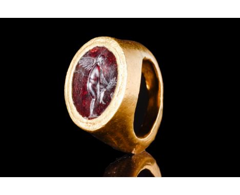 Ca. 200-100 BC.A gold ring with a round hoop and an intaglio of winged Eros. Eros stands in a graceful pose, facing to the ri