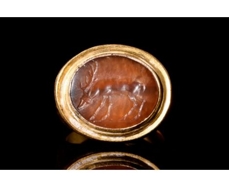 Ca. 300-100 BC.A gold ring with a flat hoop and a sizeable bezel holding a carnelian intaglio with a detailed image of a stag