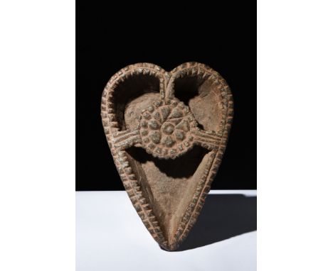 Ca. 200 AD.A heart-shaped oil lamp with rounded partitions for oil, framed by a serrated rim. The exterior features an intric