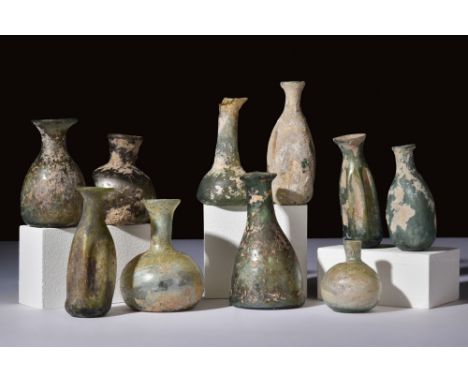 Ca. 100-300 AD.A set of 10 glass flasks, each with unique features. Some have vertical indentations, creating textured surfac