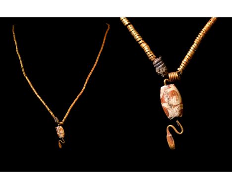 Ca. 332-30 BC.A necklace composed of a tightly coiled gold strip, centred by an agate cylinder with a drop shaped finial. Bel