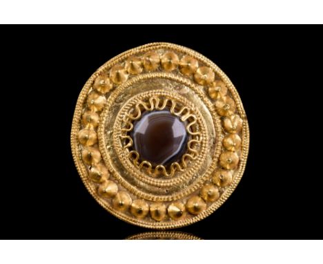 Ca. 400-300 BC.A gold brooch with a circular plate and a beautiful agate cabochon at the centre, skilfully secured by gold th
