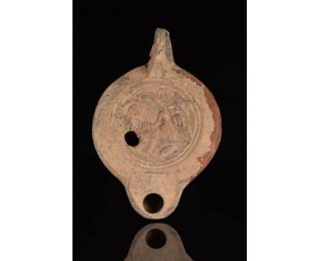 Ca. 300 AD.A terracotta oil lamp of Loeschcke type VIII. It has a circular handle and a workshop mark on the bottom. It also 