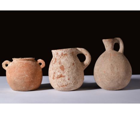 Ca. 2000-1000 BC.A set of three terracotta vessels: a bulbous jar with an everted rim and small handles, a pear-shaped cup wi