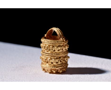 Ca. 100-200 AD. A gold pyxis with a tubular body, ornate surface details and arched handle. The exterior surface is resplende