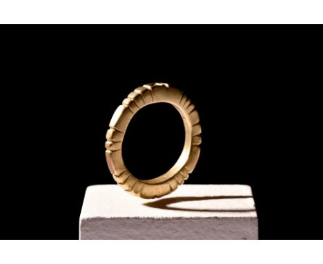 Ca. 900-1100 AD.A gold ring with slightly flat sides, adorned with a pattern of evenly spaced incisions. There are two facing