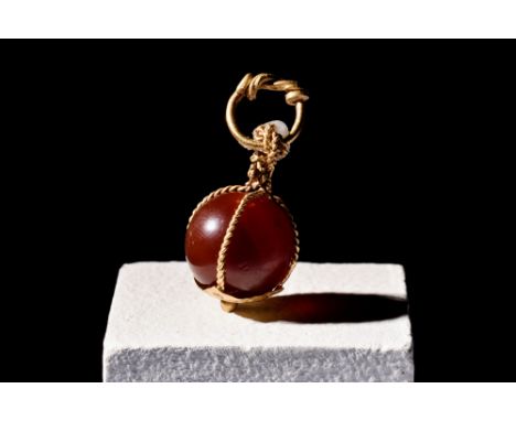 Ca. 900-1100 AD.A Viking carnelian bead in possibly later high carat gold setting, comprised of woven, cage-like golden wire,
