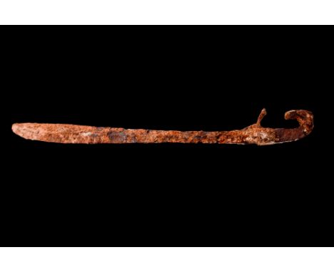 Ca. 400 BC.A Greek iron falcata, comprised of a heavy single-edged blade widening towards the point. A handle with a curved p