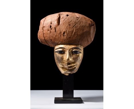 New Kingdom, Ca. 1550-1069 BC. A wooden mummy mask depicting a gilded face, arching black eyebrows, almond-shaped eyes with c