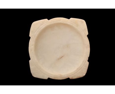 Ca. 2000 BC.A carved alabaster bowl with a flat rim and a low disc foot. Triangular corners are decorated with a double incis