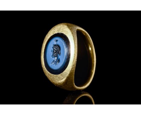 Ca. 100-200 AD.A gold ring with a round and curved design, holding a nicolo intaglio of Serapis. The Greco-Egyptian god is li
