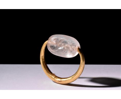 Ca. 500-400 BC.A gold swivel finger ring featuring a rock crystal scaraboid engraved with a griffin. Very well preserved and 
