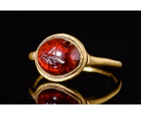 Ca. 100 AD.A delicate gold ring has a slender round hoop. It features a garnet cabochon with an engraved cricket. Size: D:15.