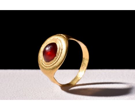 Ca. 900-1100 AD.A gold finger ring with a flat hoop that gently widens and ends in a large circular bezel. The bezel is caref