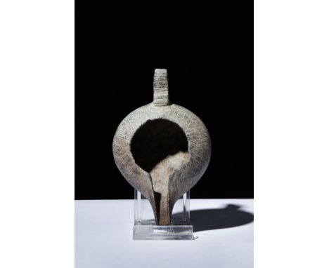 Ca. 300 AD.A stone oil lamp with a smooth, rounded shape. It has a long, thin spout and a handle on the back. The lamp's surf