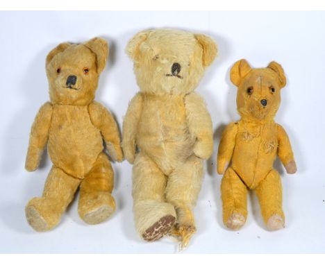 An early 20th century golden plush teddy bear - amber eyes and articulated limbs with faun pads, 34cm high, together with two