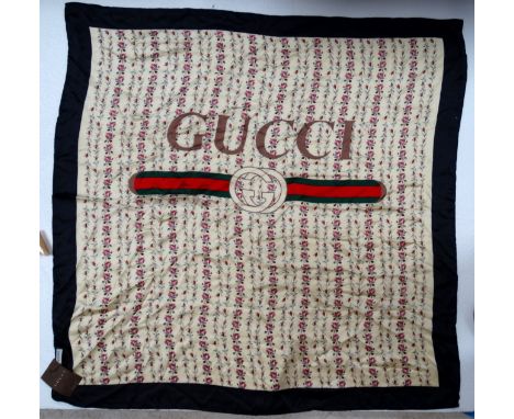 A Gucci silk scarf - floral design on a cream ground with black boarder and logo to centre, swing tag attached with original 
