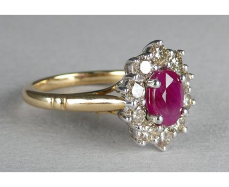 A 9ct gold ruby and diamond dress ring - the oval central stone within a band of diamonds, size N, 3.8g