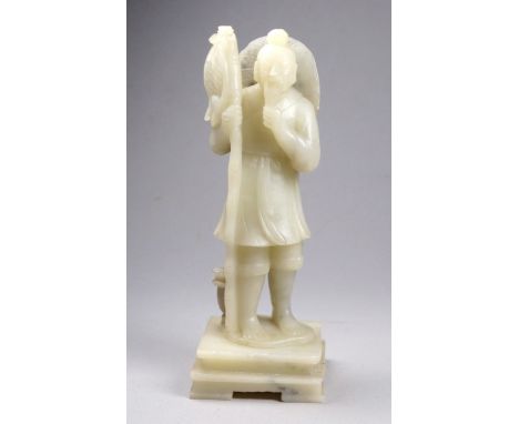 An early 20th century carved jade figure of a fisherman - standing stroking his beard and raised on a square stepped base, he