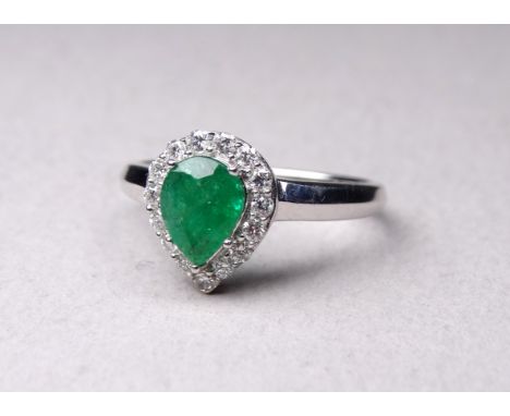 A 9ct white gold emerald and diamond ring - with pear shaped central stone within a band of diamonds, size N, 2.8g