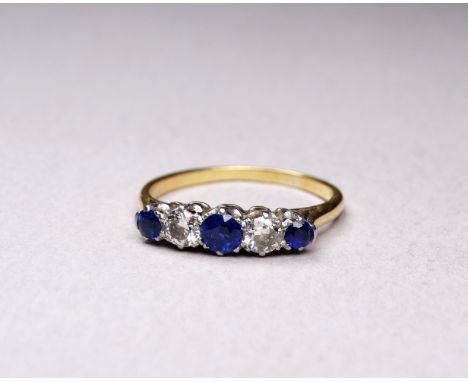 A yellow metal sapphire and diamond three stone ring - claw set with graduated stones, size N, weight 2.7g.