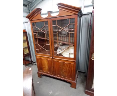 George III mahogany bookcase, the broken arch pediment over astragal glazed doors and two fielded cupboard doors on bracket f