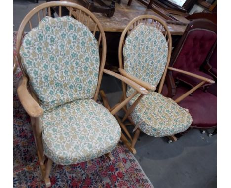 An Ercol pair of pale wood rocking arm chairs with upholstered back and seat.