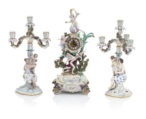 A Meissen clock on stand and two candelabraLate 19th centuryThe clock surmounted by Psyche sitting on a globe, with Cupid and