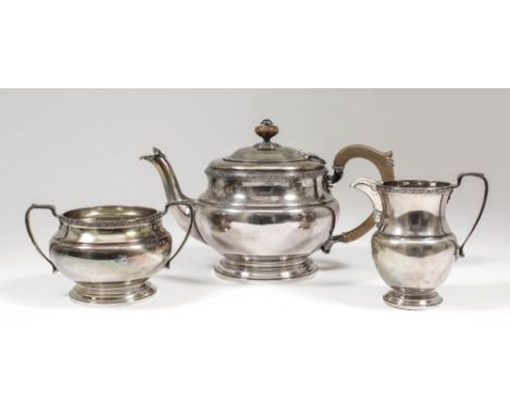 A George V silver circular three piece tea service, the moulded rims cast with oval bead ornament, angular loop handles, bulb