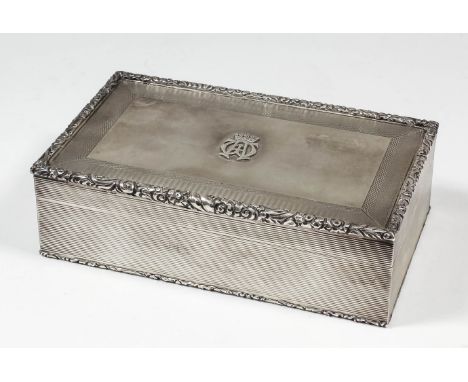 A George VI silver rectangular cigarette case with floral and leaf scroll mounts, the lid with applied crowned monogram withi