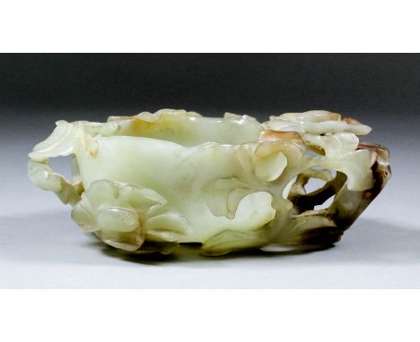 A Chinese celadon jade one handled bowl with brown inclusions, pierced and carved with leaves, 7ins (17.8cm) x 4.75ins (12cm)