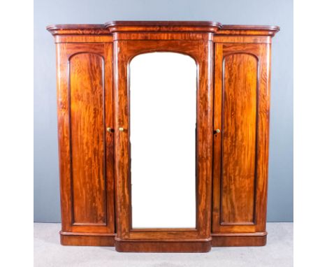 A Victorian mahogany break front wardrobe with moulded cornice, the centre fitted four sliding trays and three drawers enclos