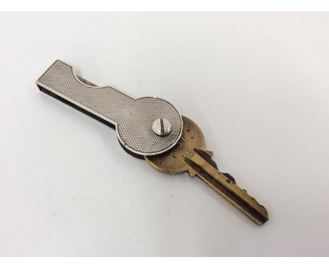 A silver yale key cover, by Asprey & Co., with engine turned decoration