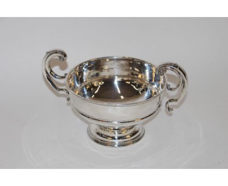 An early 20th Century silver trophy cup, having scrolled handles, central raised girdle on a circular spread foot, hallmarked