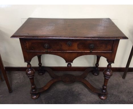 A reproduction walnut side table, in the 18th Century style, having cross-banded top above single drawer, raised on turned cu