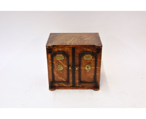 A Victorian oak ebonised and brass mounted tea caddy, in the form of a safe, the doors opening to reveal three interior drawe