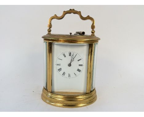 An oval brass cased carriage clock, having white enamel Roman numeral dial, repeat movement striking on a gong, 14.5cm high
