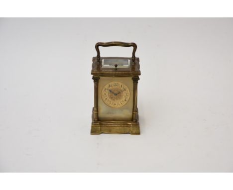 A brass cased carriage clock, the serpentine case with corinthian columns and scrolled capitals to the corners, circular fili