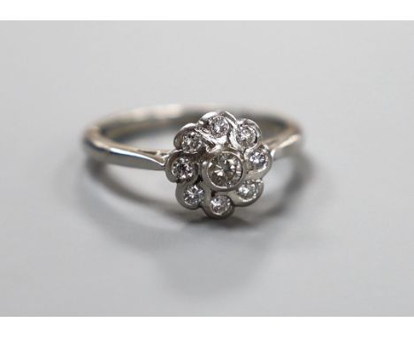 A modern platinum and collet set nine stone diamond flower head cluster ring, size O, gross weight 5.6 grams, total diamond w