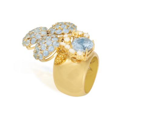 AN AQUAMARINE RINGSet with a faceted oval-shaped aquamarine, highlighted by claw-set circular-cut aquamarines to one side, su