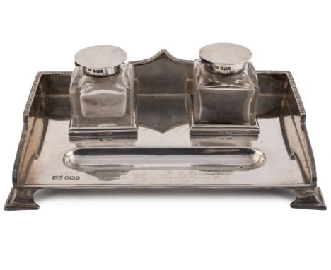 A George V silver inkstand, with shaped and beaded gallery, fitted with a pair of square section cut glass inkwells with hing