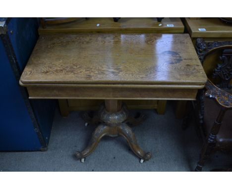An oak card table the twin flap top on a carved column and splayed legs