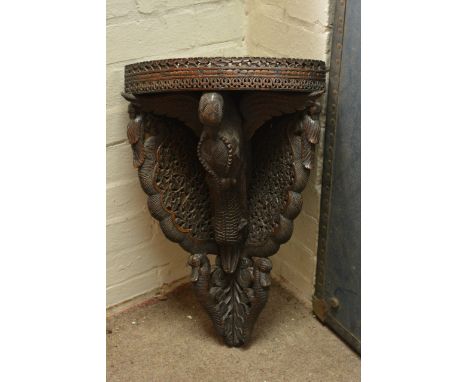 An ornately carved corner shelf unit depicting birds and other creatures.