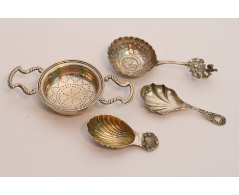 Two silver cady spoons, a silver tea strainer, and a Continental white metal spoon (4)