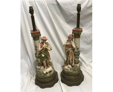 Pair of continental pottery figurine table lamps, Male and Female with goats and lambs beside a column with leaf vine decorat